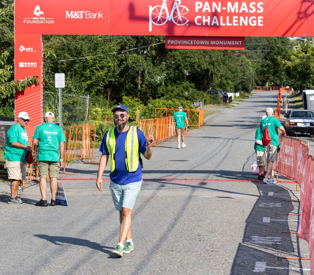 Charles in his security lead vest giving a peace sign at the Pan-Mass Challenge finish line in Provincetown